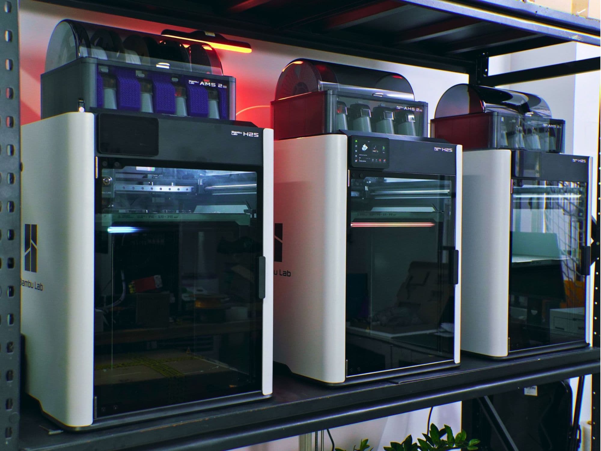 A row of Bambu Lab H2S 3D printers with AMS 2 units at the Technix AM workshop